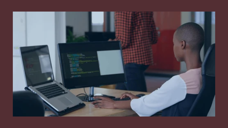 A developer coding on a laptop with AI framework tools displayed on screen in a modern workspace
